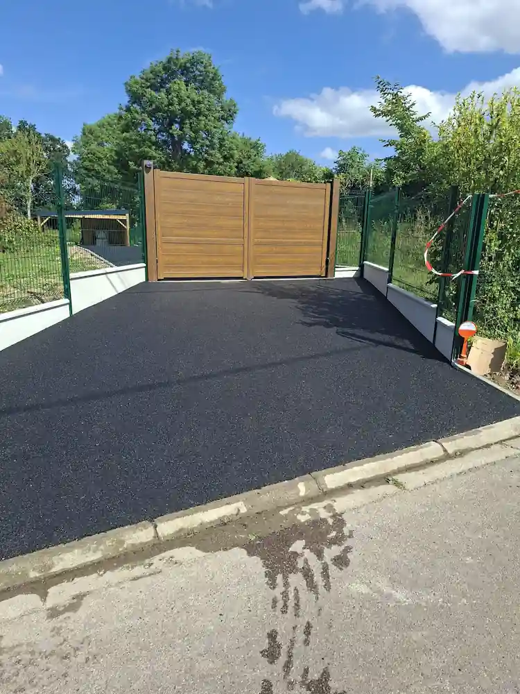 Allée en enrobé menant à un portail aluminium aspect bois
